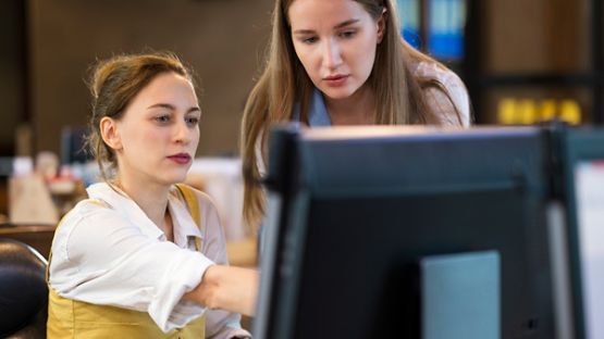 Two women looking at something on a computer.