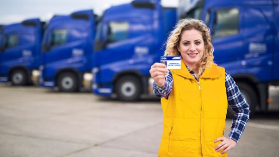 Woman truck driver proudly holding commercial driving license. 