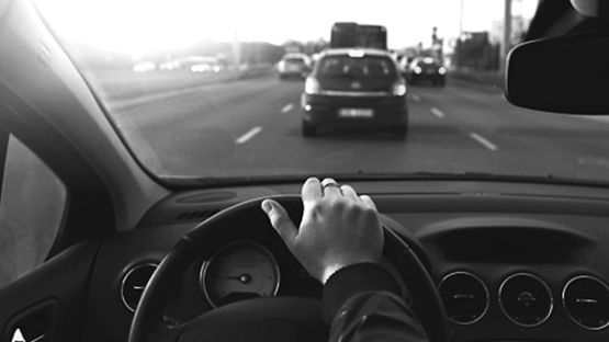 Close up of a person's hand on a steering wheel
