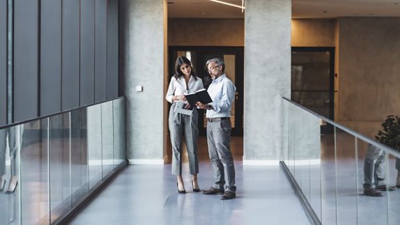 Deux professionnels qui examinent un document dans le couloir d’un bureau 