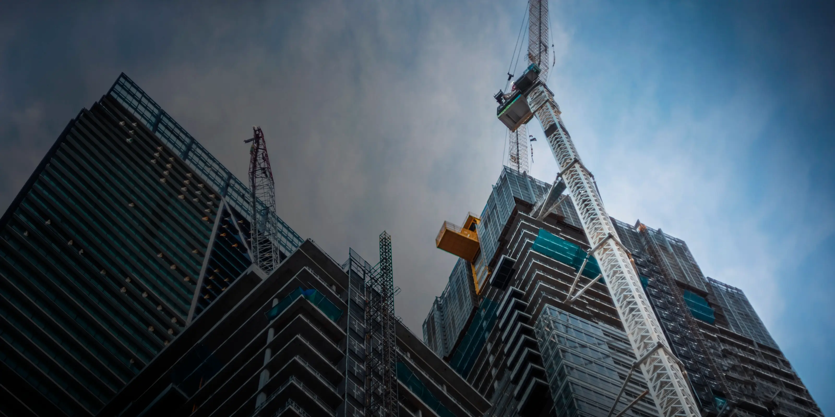 Immeubles de grande hauteur en construction avec des grues sur un chantier urbain.