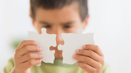 Young boy holding two jigsaw puzzle pieces