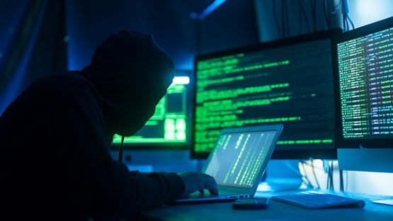 Masked man hacking into a laptop