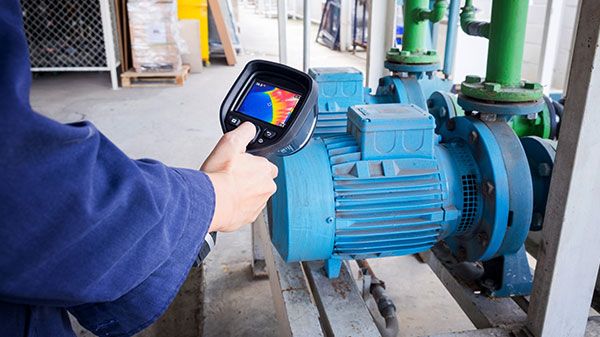 Technician using thermal imaging camera to check the temperature in a factory