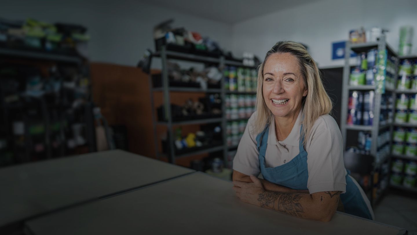 Woman leaning on counter working in paint supply store