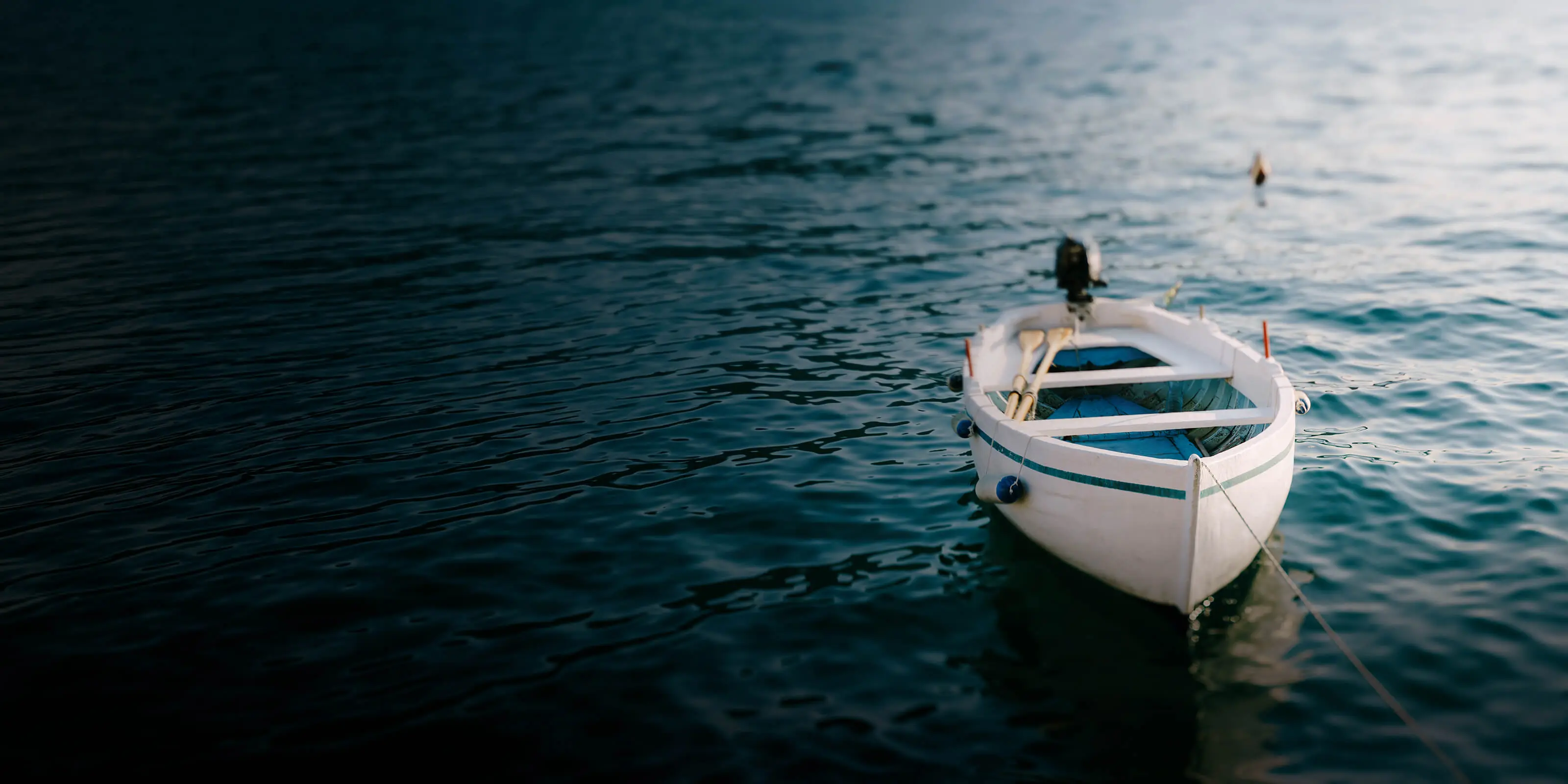 Petit bateau flottant sur une eau calme et attaché à l’aide d’une corde.