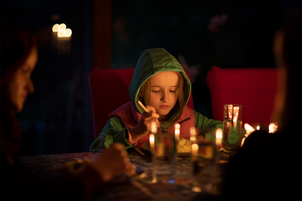 Famille prenant son repas à une table éclairée à la bougie lors d’une panne de courant.