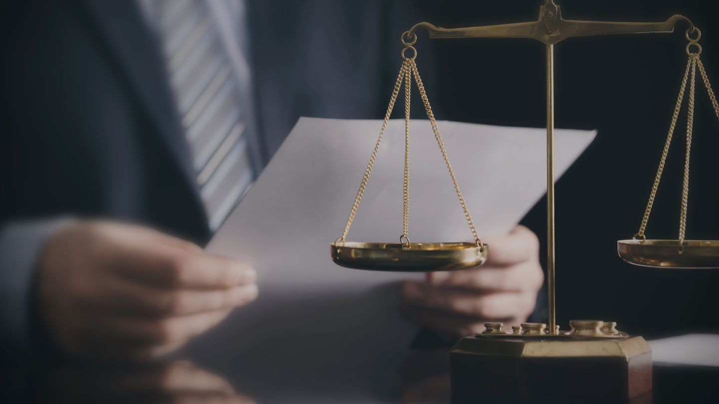 Gros plan sur un avocat dans un bureau avec une balance de la justice sur la table.
