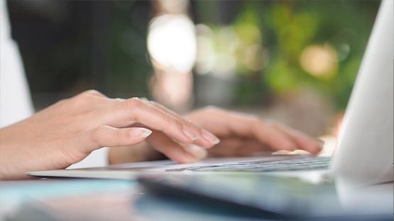 Close up of hands typing on a laptop keyboard.