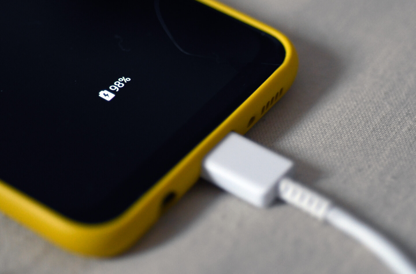Gros plan d’un téléphone intelligent branché à un câble de recharge avec l’indicateur de chargement de la batterie affiché.