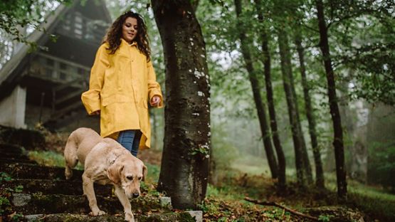 Young woman in yellow rain jacket walking her dog