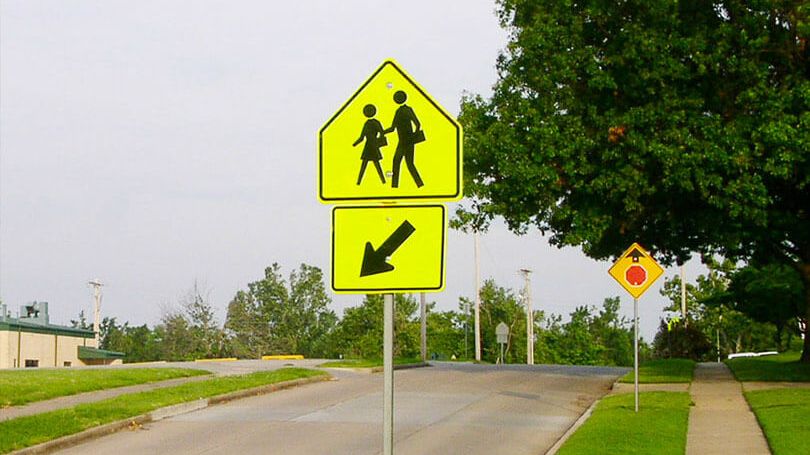 Un panneau de signalisation, à vocation sécuritaire, indique la présence probable de piétons dans une zone scolaire 