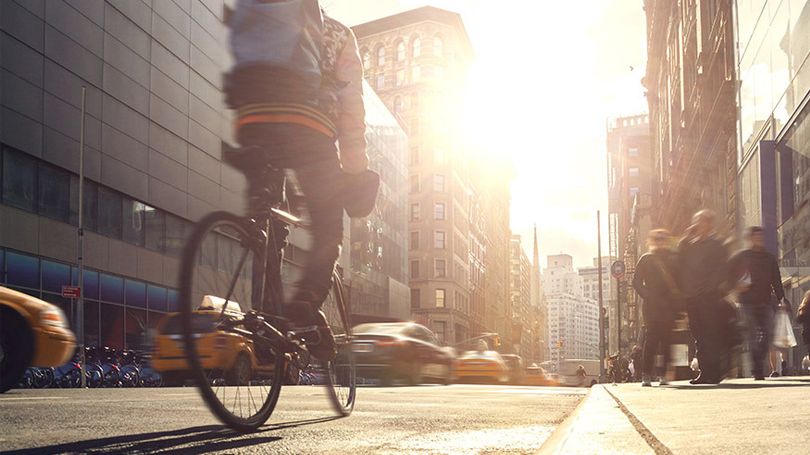 Une personne circule à vélo dans une rue passante 