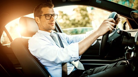 A man happily driving to work in his car. 