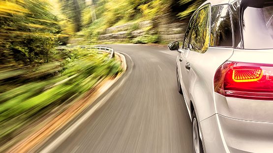 Close-up of a silver car driving along a curved road.