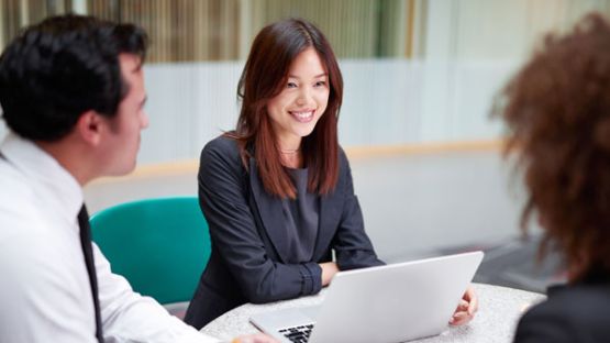 Female professional sitting with a laptop and another male and female colleague