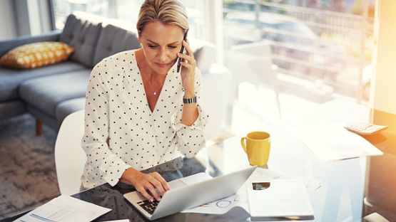 Woman on phone call, looking at laptop