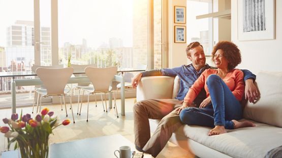 A happy couple enjoying a sunny afternoon on their living room couch in their condo