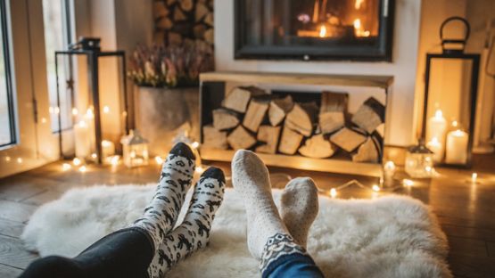 Couple’s feet in front of a cabin fireplace.