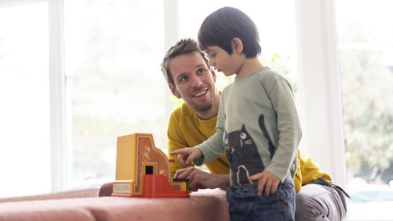 Un père et son fils s’amusent avec une mini-caisse enregistreuse.