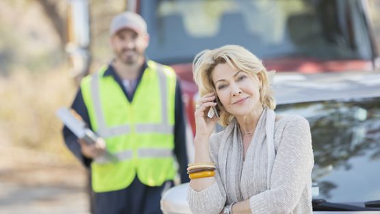 Male tow truck operator loading vehicle on tow truck.