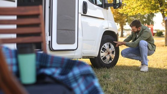 A man checking the tires on his recreational vehicle.