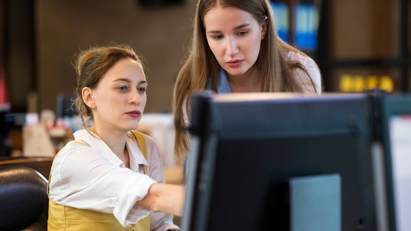 Two women looking at something on a computer.
