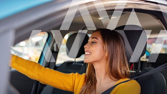 A closeup image of a driver, calmly and carefully adjusting her rear view mirror to ensure a safe journey