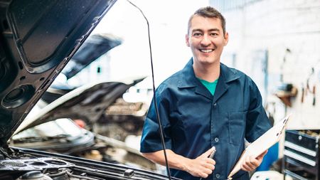 Smiling mechanic fixing car after claim.