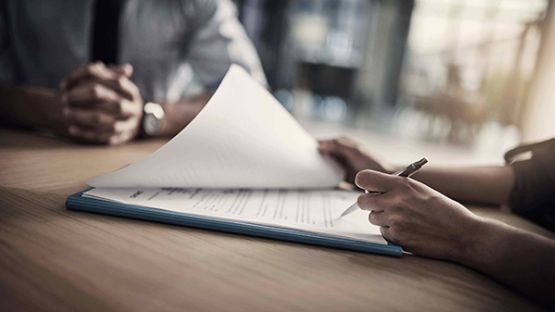 Close up of a man and woman completing insurance paperwork at a desk.