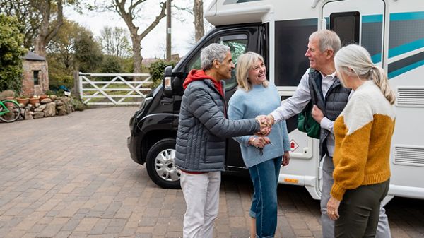 A person handing another person keys to the parked rv for RV- sharing insurance