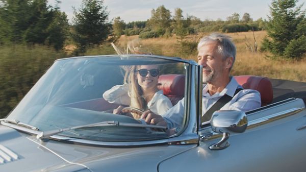 Un couple heureux fait une balade dans une voiture ancienne