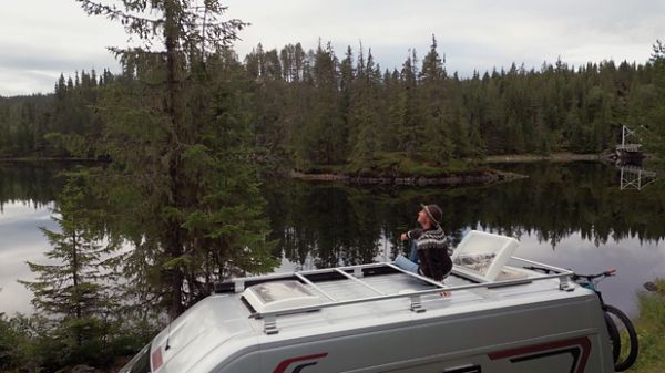 A man enjoying a scenic view on top of a RV