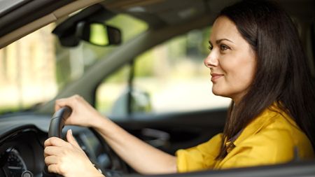 Side view of a woman happily driving her car.