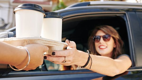 Une femme commande un café dans un service à l'auto