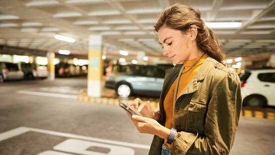 Femme dans un stationnement, utilisant la fonction Localiser ma voiture de l’appli Conduimatic Aviva