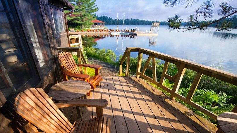 Muskoka chairs on a porch overlooking the lake.